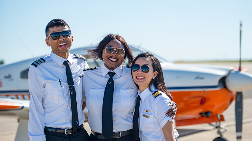 smiling students in front of plane