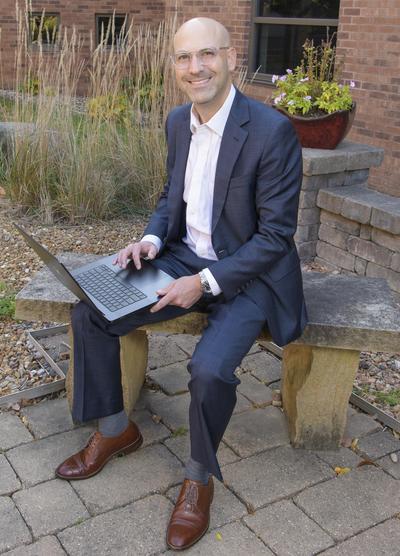 Smiling man on bench with laptop